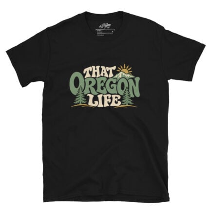 Black Groovy Oregon Tee with retro That Oregon Life lettering, evergreen trees, a mountain, and a golden sun on the front
